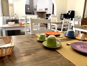 A dining area with a wooden table set for four, surrounded by white chairs. - Domo Achenza (Terralba)