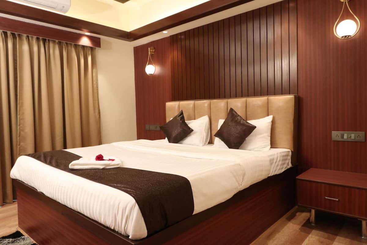 Ein Hotelzimmer mit einem großen Bett, Holzwandverkleidung, einem Nachttisch und einer wandmontierten Leuchte.