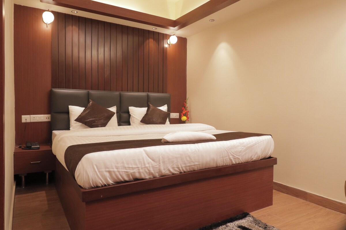 A modern bedroom with a wooden headboard, a large bed with white bedding, and a nightstand with a phone.
