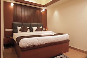 A modern bedroom with a wooden headboard, a large bed with white bedding, and a nightstand with a phone. - The Lake Hotel (Kolkata)