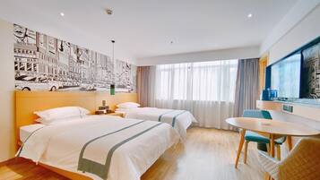 A hotel room with two beds, a dining area, a large window with curtains, and a wall mural.