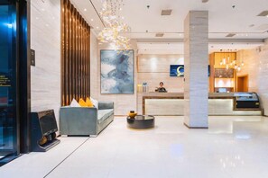 A modern hotel lobby with a reception desk, seating area, and a large abstract painting.