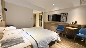 Ett hotellrum med en säng, ett skrivbord, två stolar, en tv och ett konstverk som hänger på väggen.