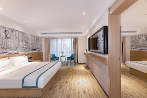 Habitación de hotel con una cama grande, dos sillas, un televisor y un mural con vista a la ciudad.