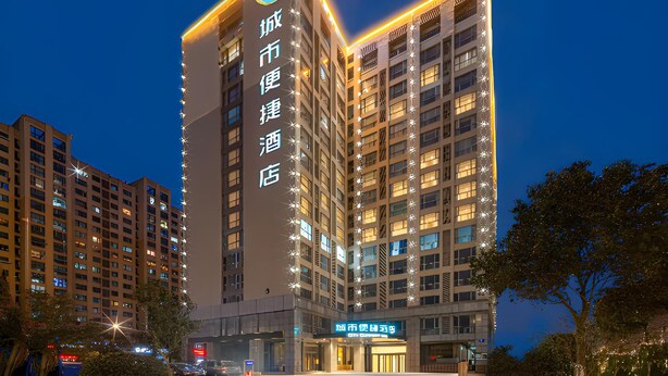 En hotellbyggnad med flera våningar, upplyst skyltning, en framträdande entré och fri utsikt över den omgivande stadsmiljön.