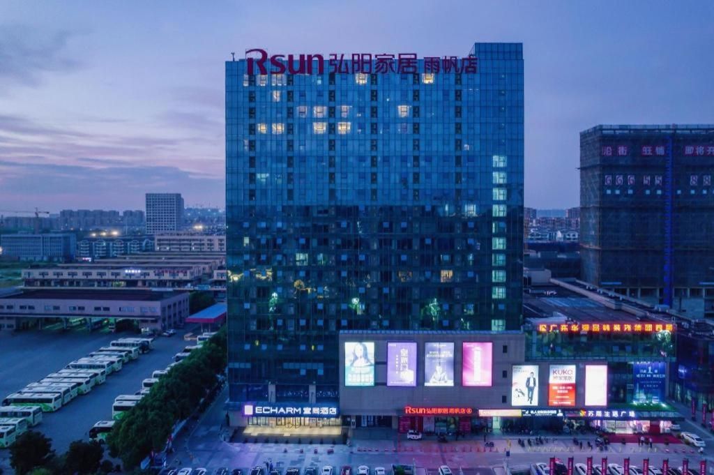 A high-rise building with multiple floors, a large parking lot in front, and several billboards.