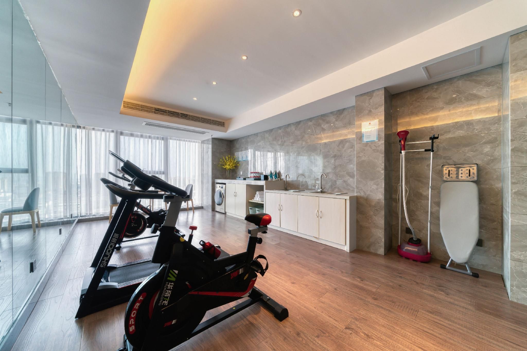 A modern home gym with two stationary bikes, a washing machine, and a steam cleaner.