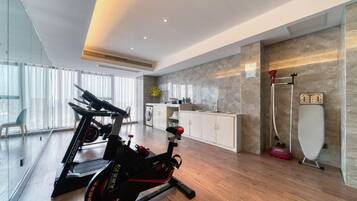 A modern home gym with two stationary bikes, a washing machine, and a steam cleaner.