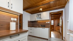 Eine moderne Küche mit Holzbalken, weißen Schränken und einer Holzarbeitsplatte.