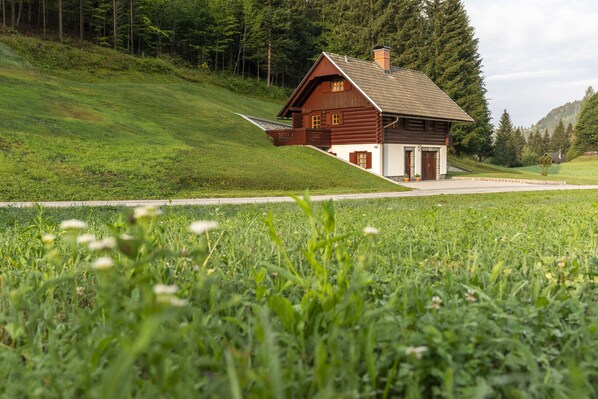 A wooden cabin with a sloped roof, a front porch, and a stone foundation.