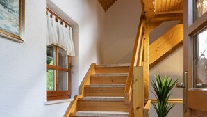Eine Holztreppe mit Blick auf ein Fenster und eine Tür.