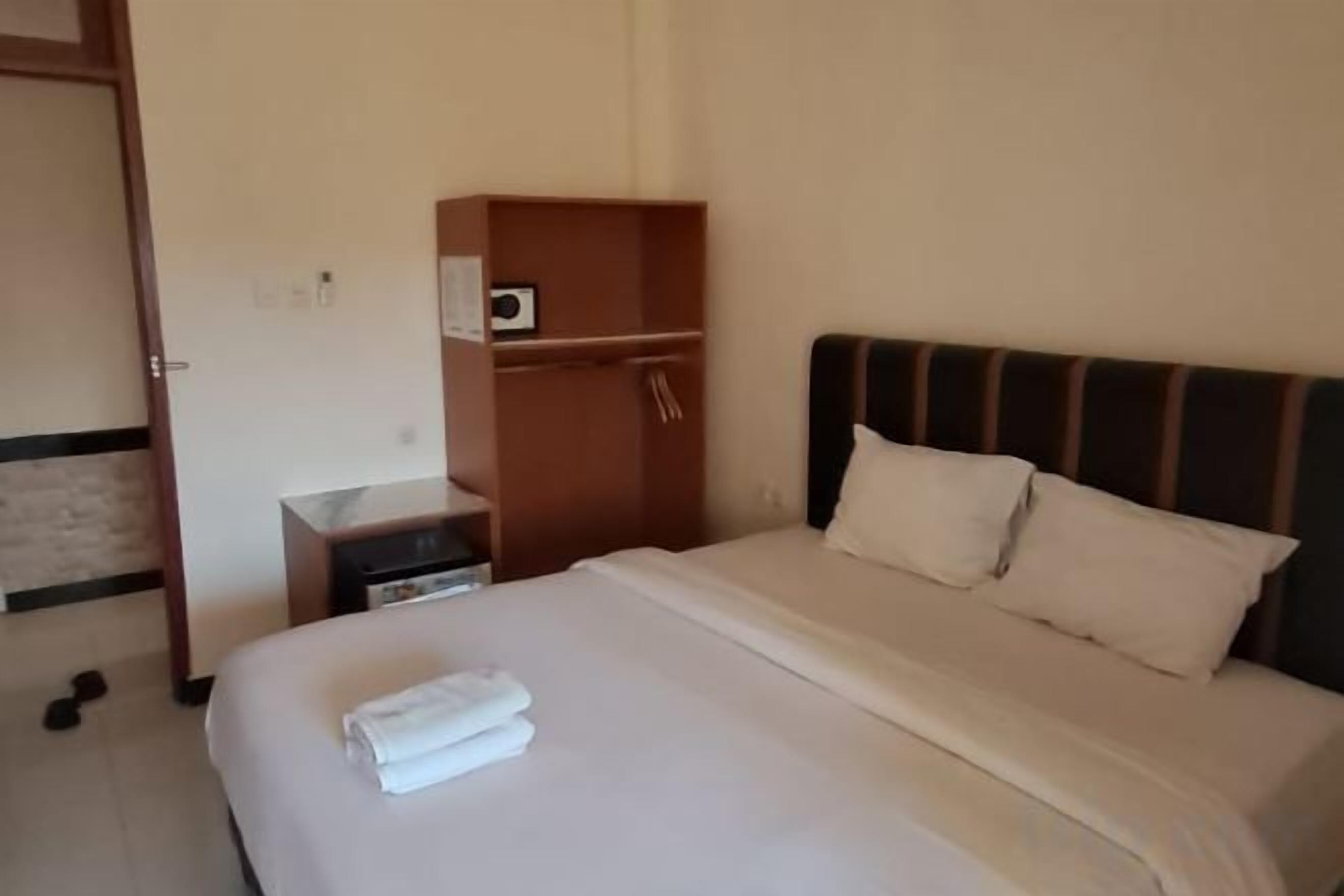 A hotel room with a bed, a nightstand, a wardrobe, and a door.