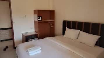 A hotel room with a bed, a nightstand, a wardrobe, and a door.