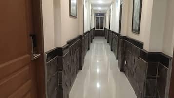 A hallway with a wooden door on the left, tiled walls, and a glossy floor.