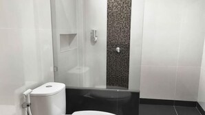 A modern bathroom with a toilet, a glass shower enclosure, and a patterned wall. - LUMBA LUMBA INN WARU (Waru)