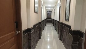 A hallway with a polished floor, dark wall trim, and a door on the left. - LUMBA LUMBA INN WARU (Waru)