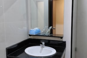 A bathroom with a white sink, a mirror, and a blue soap dispenser.
