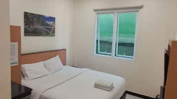 A bedroom with a bed, a window, and a painting on the wall.