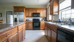 A kitchen with wooden cabinets, a stainless steel refrigerator, a microwave, a stove, and a dishwasher.