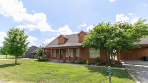 A two-story wooden building with a covered porch, a grassy lawn, and a sign reading 'HOUSING'.