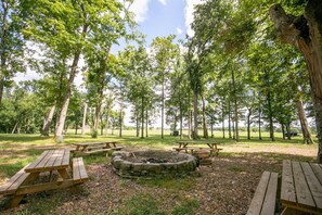 A picnic area with wooden benches and a fire pit surrounded by trees.