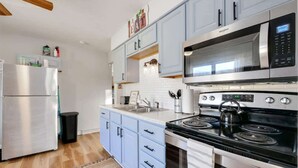 A modern kitchen with stainless steel appliances, light blue cabinets, and a black stove.