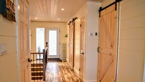 A hallway with wooden flooring, a staircase, and sliding barn-style doors.