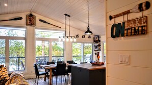 A modern kitchen with large windows, a dining area, and a cozy seating area.