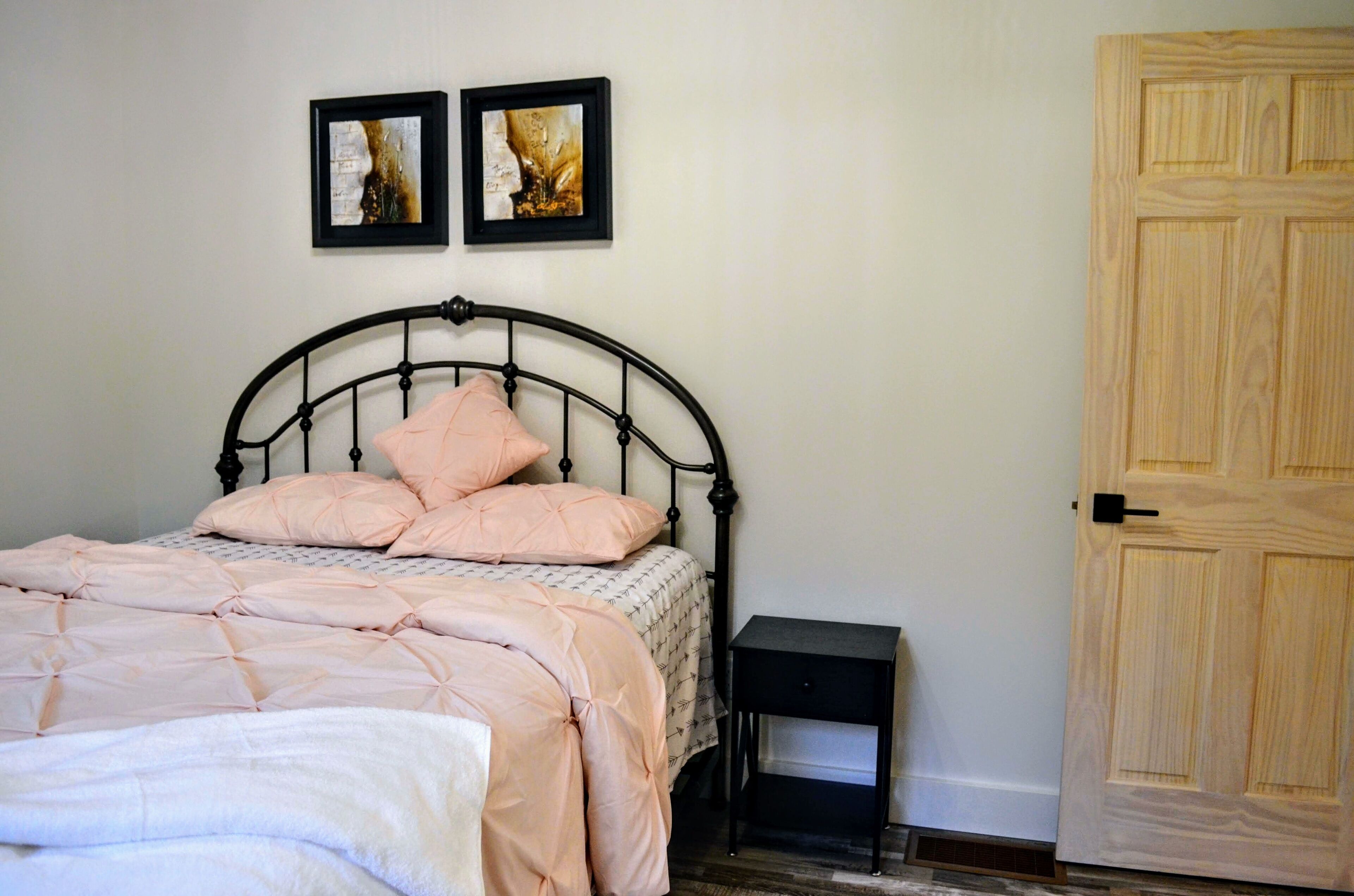 Un dormitorio con cama, mesita de noche y puerta de madera.