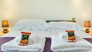A hotel room with two beds, white linens, and two packages of ginger snap biscuits on the beds. - Crown Apartments 3A - UK3380 (Newcastle upon Tyne)