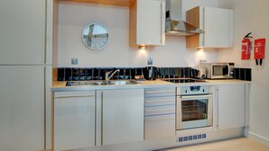 A modern kitchen with stainless steel appliances, a built-in oven, and a microwave. - Crown Apartments 3A - UK3380 (Newcastle upon Tyne)