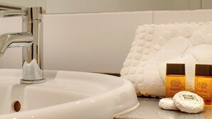 A bathroom sink with a chrome faucet, a white towel, and two bottles of shampoo. - Crown Apartments 3A - UK3380 (Newcastle upon Tyne)