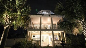 A two-story house with a balcony and a well-lit entrance. - Luxury Beach House, Private Salt Pool. Walk to the Beach (Palm Coast)