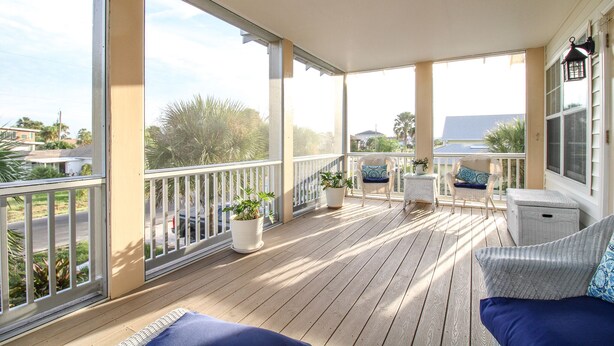 A covered porch with wooden flooring, white railings, and potted plants. There are wicker chairs and a sofa with cushions. - Luxury Beach House, Private Salt Pool. Walk to the Beach (Palm Coast)