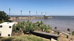 A pier extending into calm waters with a clear sky.