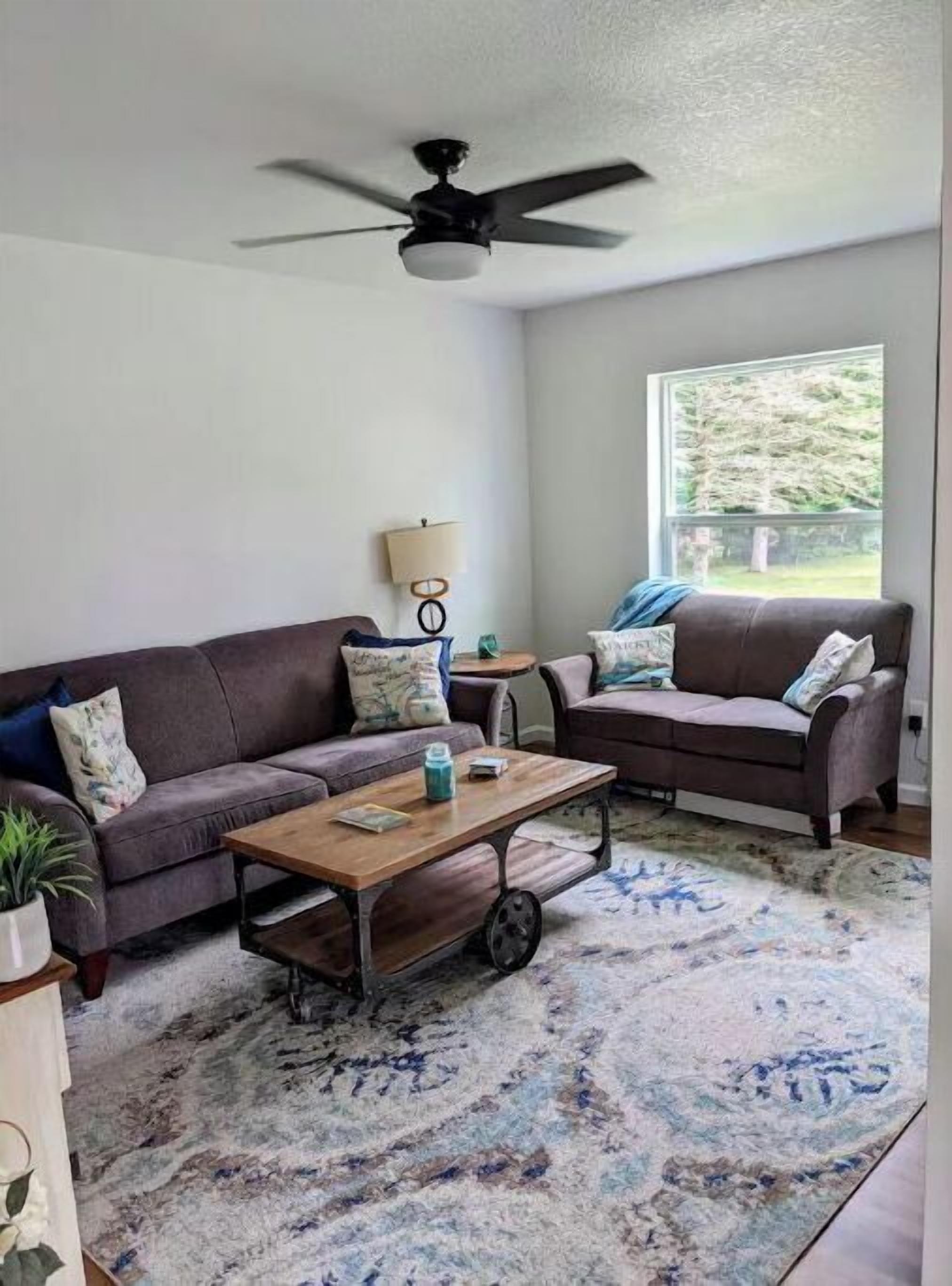 A living room with two sofas, a coffee table, a lamp, and a ceiling fan.