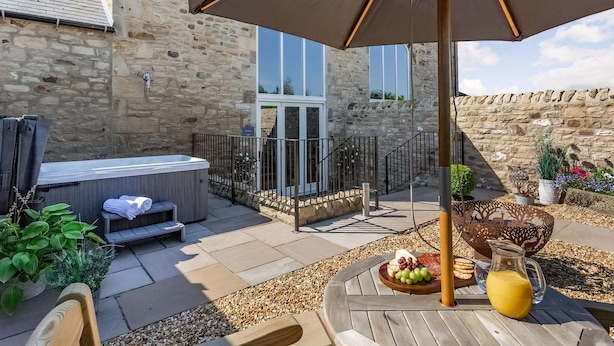 Eine Terrasse mit Whirlpool, Sitzgelegenheiten im Freien und einem Tisch mit Essen und Getränken.