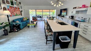 A modern kitchen with a central island, a dining area with a blue sofa, and a living room with a large window. - Romantic Keauhou Retreat - Pool + Tropical Lanai (Kailua-Kona)