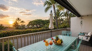 A wooden deck with a table set for two, a bowl of fruit, and two drinks. - Romantic Keauhou Retreat - Pool + Tropical Lanai (Kailua-Kona)