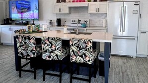 A modern kitchen with a central island, white cabinetry, and a ceiling fan. - Romantic Keauhou Retreat - Pool + Tropical Lanai (Kailua-Kona)