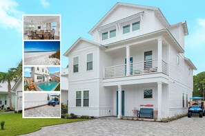 A two-story white house with a balcony, a pool, and a driveway.