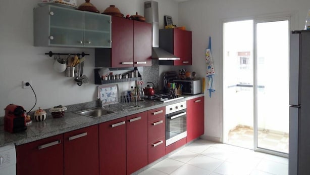 Una cocina moderna con armarios rojos, una estufa a gas y un horno empotrado.