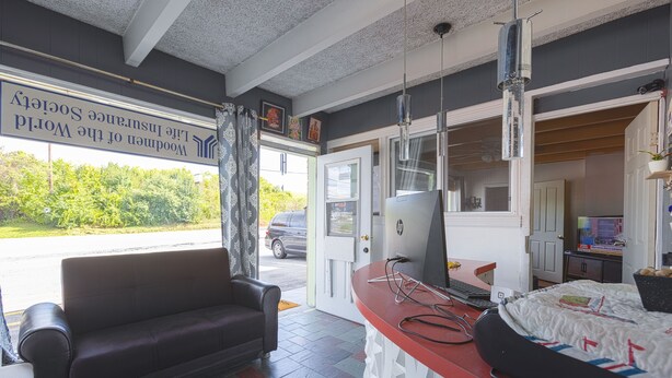 A room with a sofa, a desk with a computer, and a bed with a quilt. - Sonrise Inn Lincoln Hwy By OYO (Breezewood)