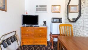 A compact room with a wooden dresser, a television, a microwave, a chair, and a dining table. - Sonrise Inn Lincoln Hwy By OYO (Breezewood)