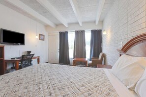 A hotel room with a large bed, a desk with a chair, a television, and a view of the outdoors through the window. - Sonrise Inn Lincoln Hwy By OYO (Breezewood)