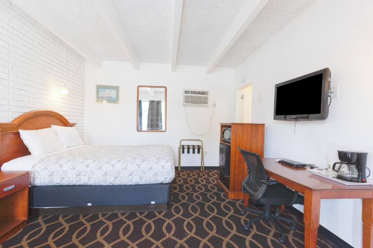 Una camera d'albergo con un letto, una scrivania, una sedia, una televisione e una macchina per il caffè.