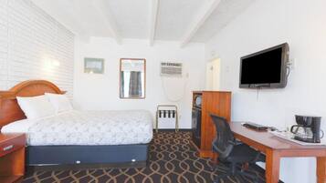 Une chambre d’hôtel équipée d’un lit, d’un bureau, d’une chaise, d’une télévision et d’une machine à café.