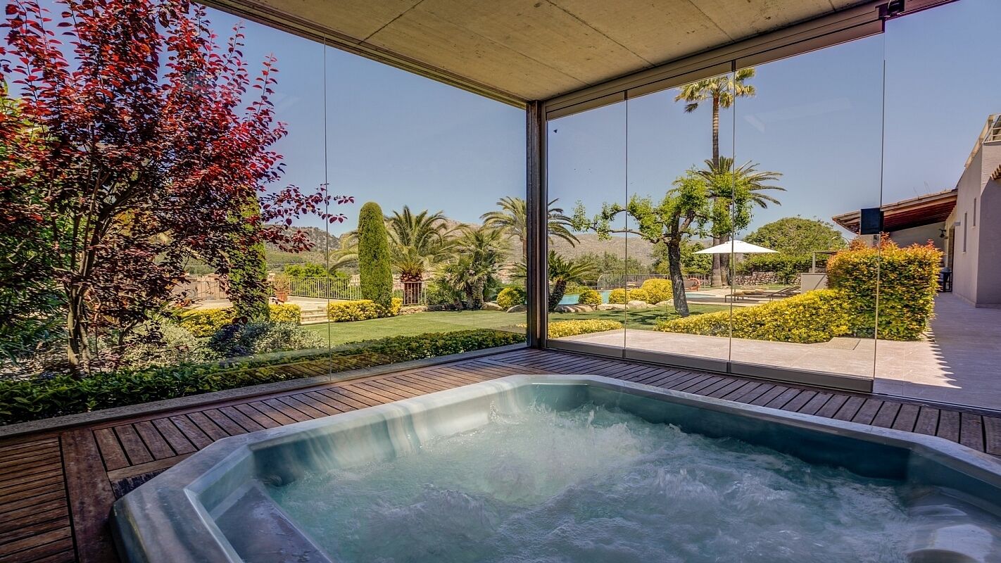 A hot tub with a view of a landscaped garden and palm trees.