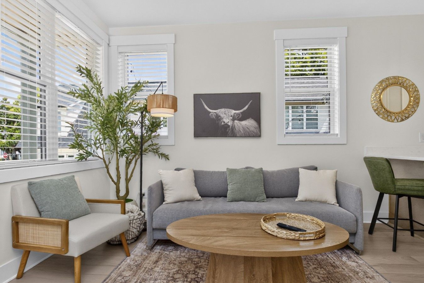 A modern living room with a grey sofa, a round wooden coffee table, and a large plant.