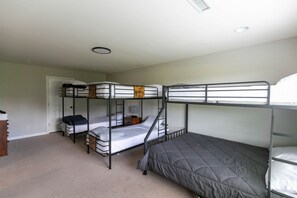 A dormitory room with bunk beds, a door, a small table, and a lamp. - Sleeps 14 on a Duck River ranch: 4 en suite bedrooms, patio, fishing, horses (Normandy)